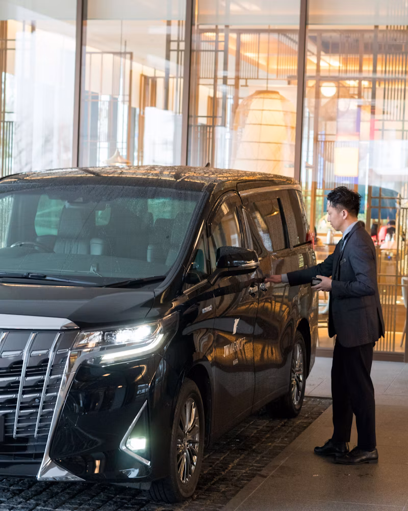 Professional chauffeur opening the door of a luxury MPV